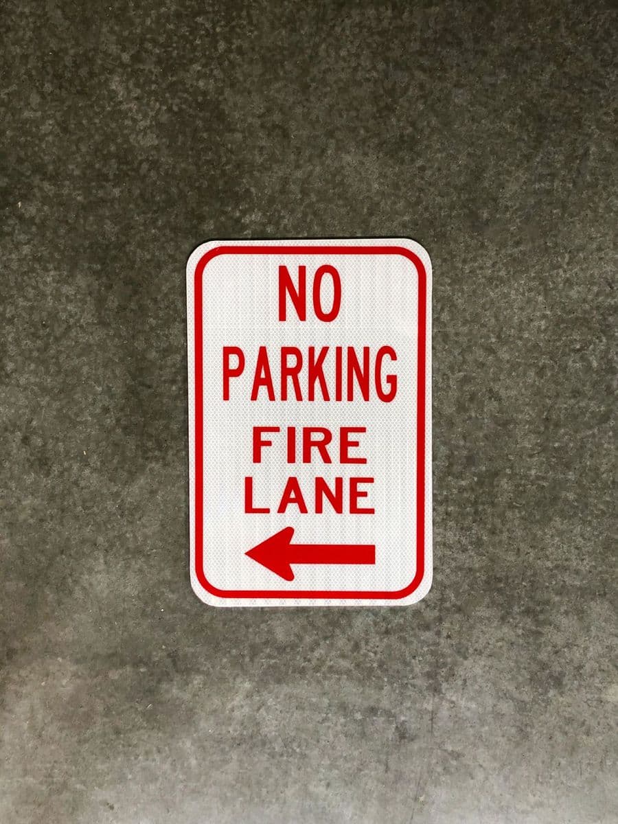 Red and white No Parking Fire Lane sign with arrow