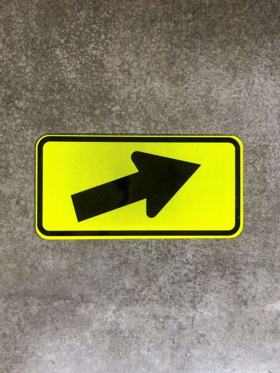 Fluorescent yellow-green diagonal arrow sign for school zones